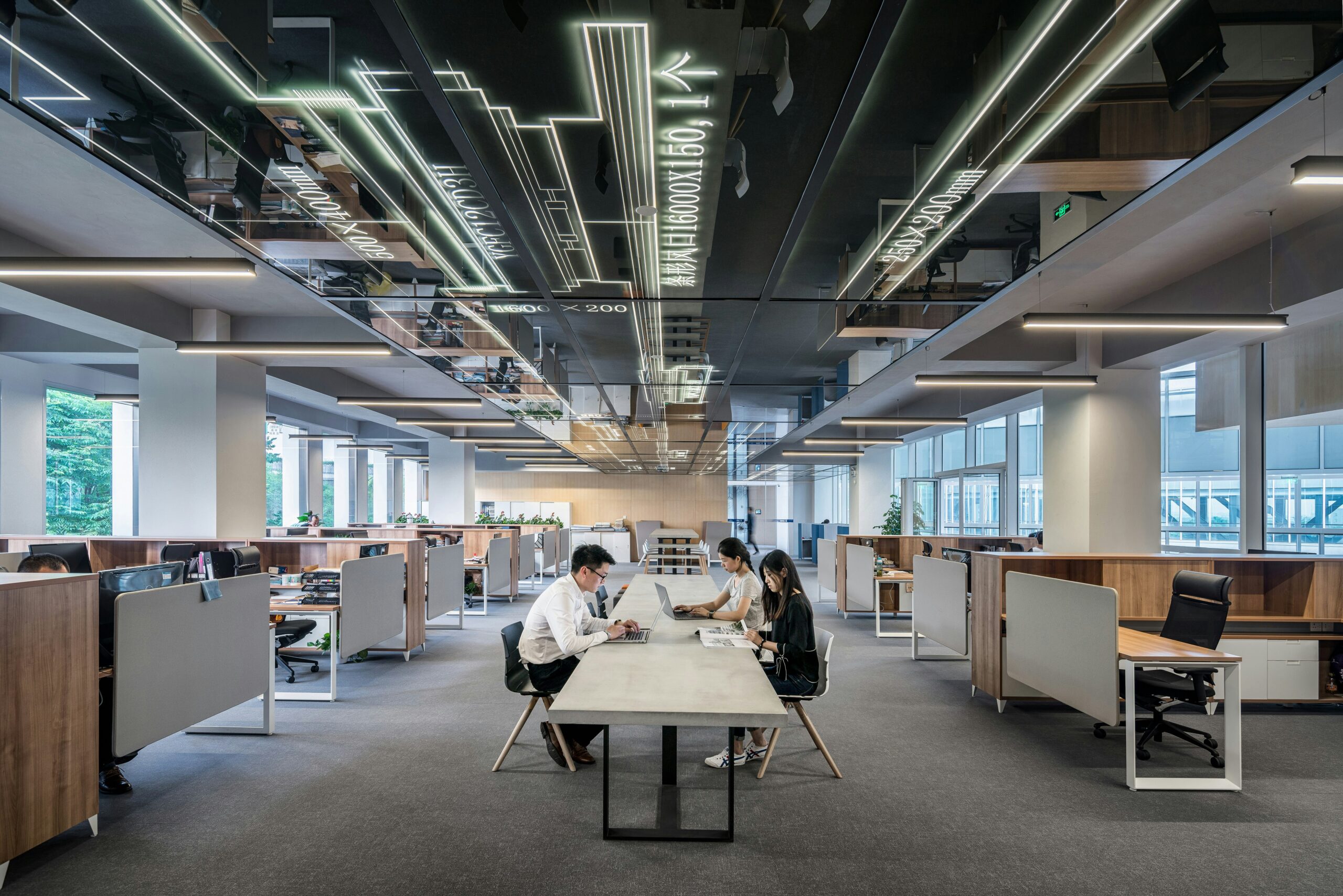 An open office with people working at desks and discussing cyber security tips.