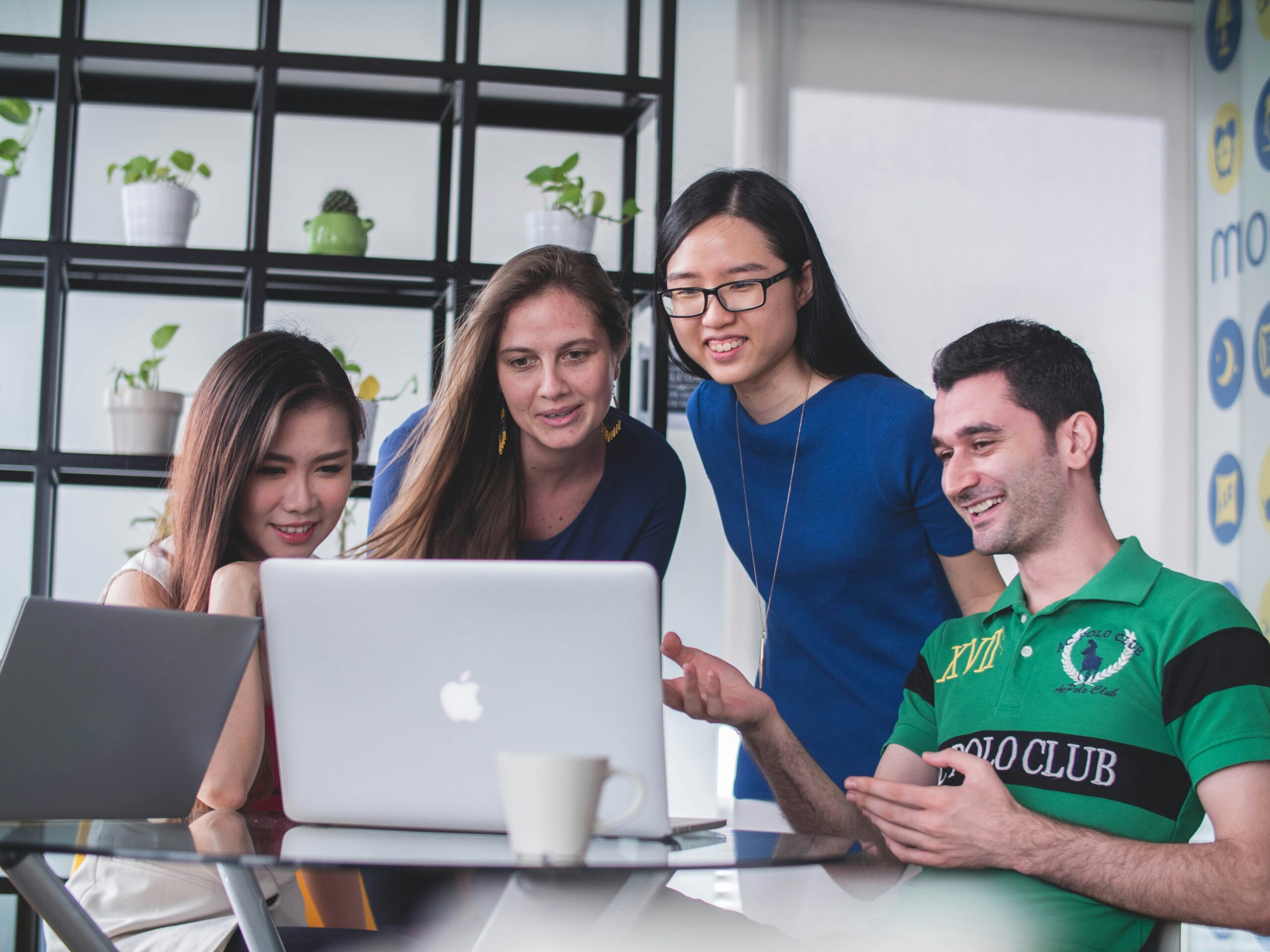 Four colleagues are gathered around a table, looking at a laptop screen that breaks down the differences between Microsoft Office and Office 365.
